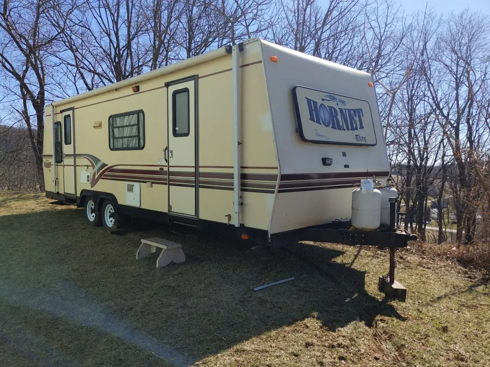 Yellow Hornet RV parked on grassy area.