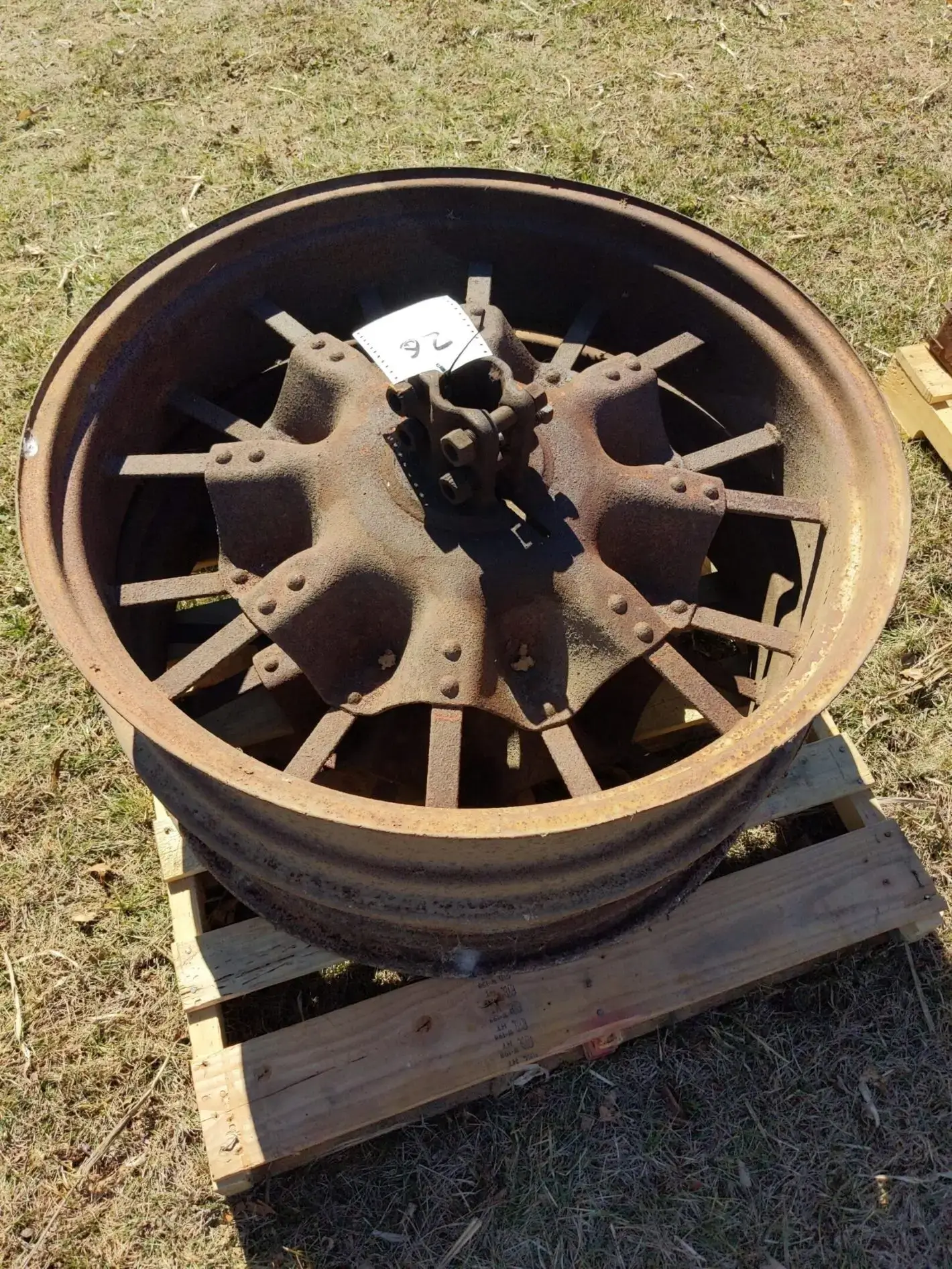 Rusty metal wheel on wooden pallet.
